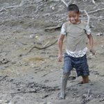 Boy wades through mud.