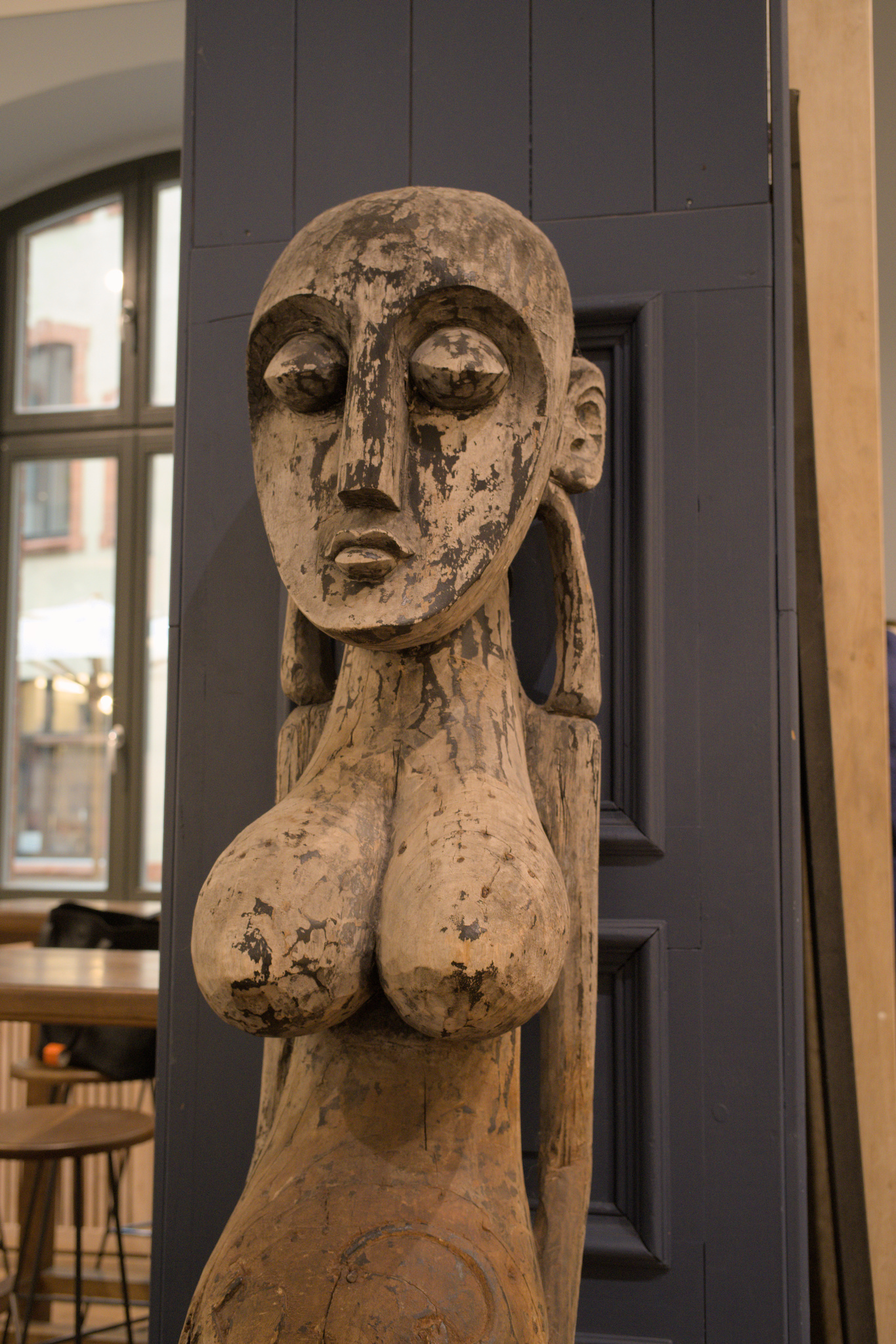 Tall primitive-style wood carving of a pregnant woman.